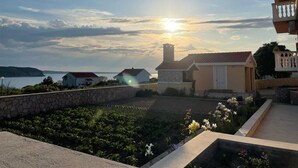 A residential area with a stone wall, a garden with flowers, and houses with a view of the sea. - Apartments Adriatic (Razanac)