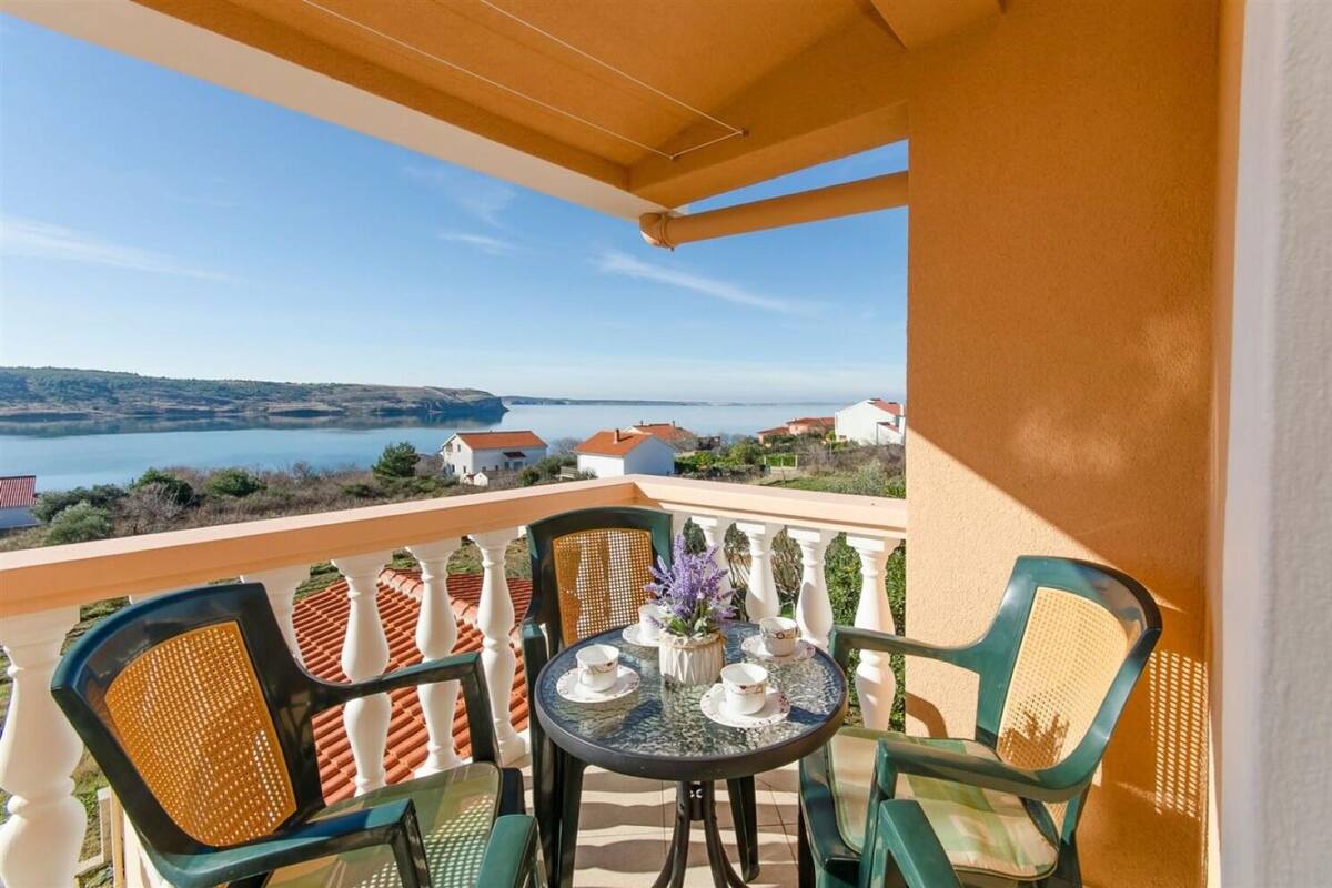 En balkon med et bord og stole, der udover et smukt udsigtspunkt over et sølandskab og bygninger.