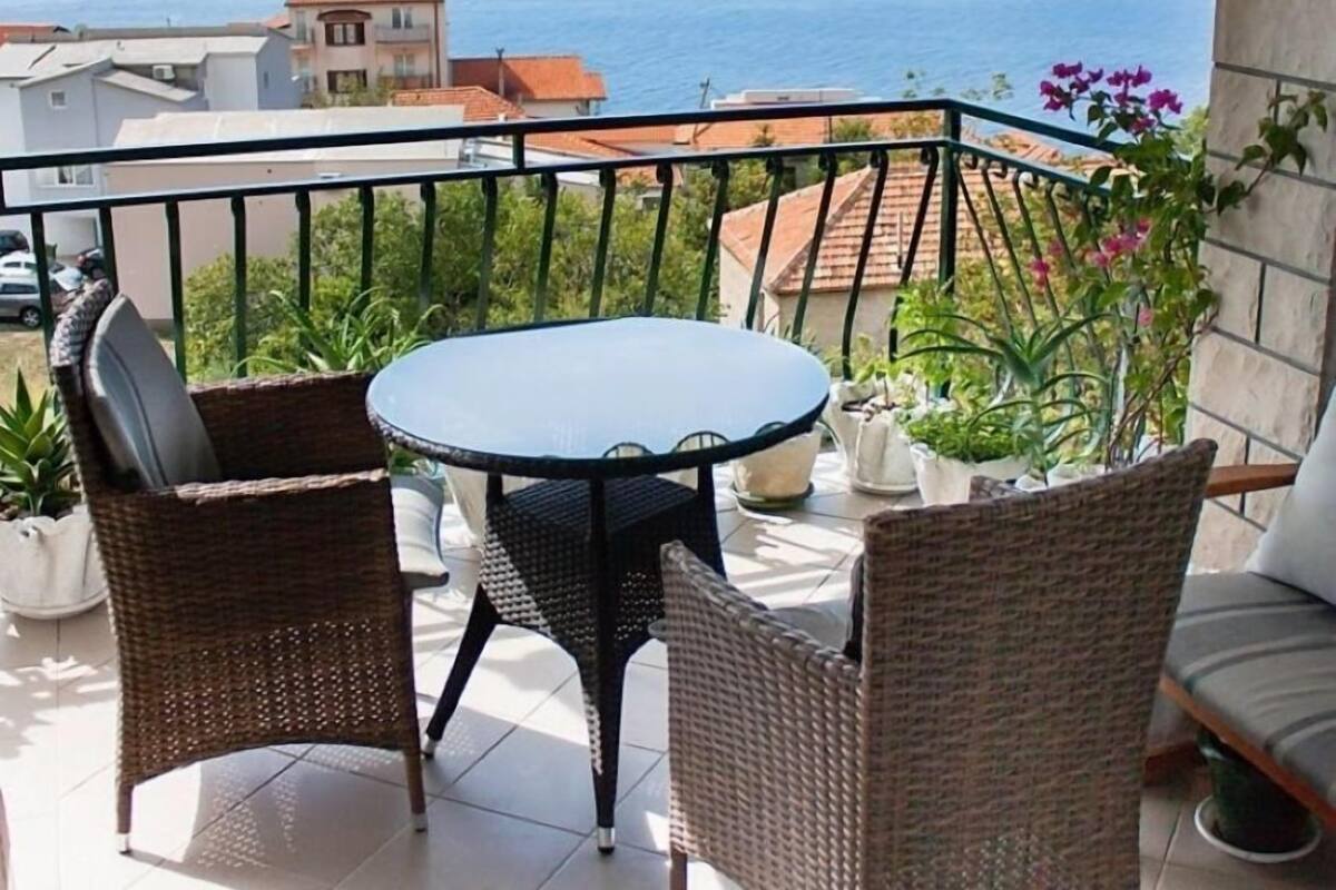 A balcony with a striped awning, wicker furniture, and potted plants.