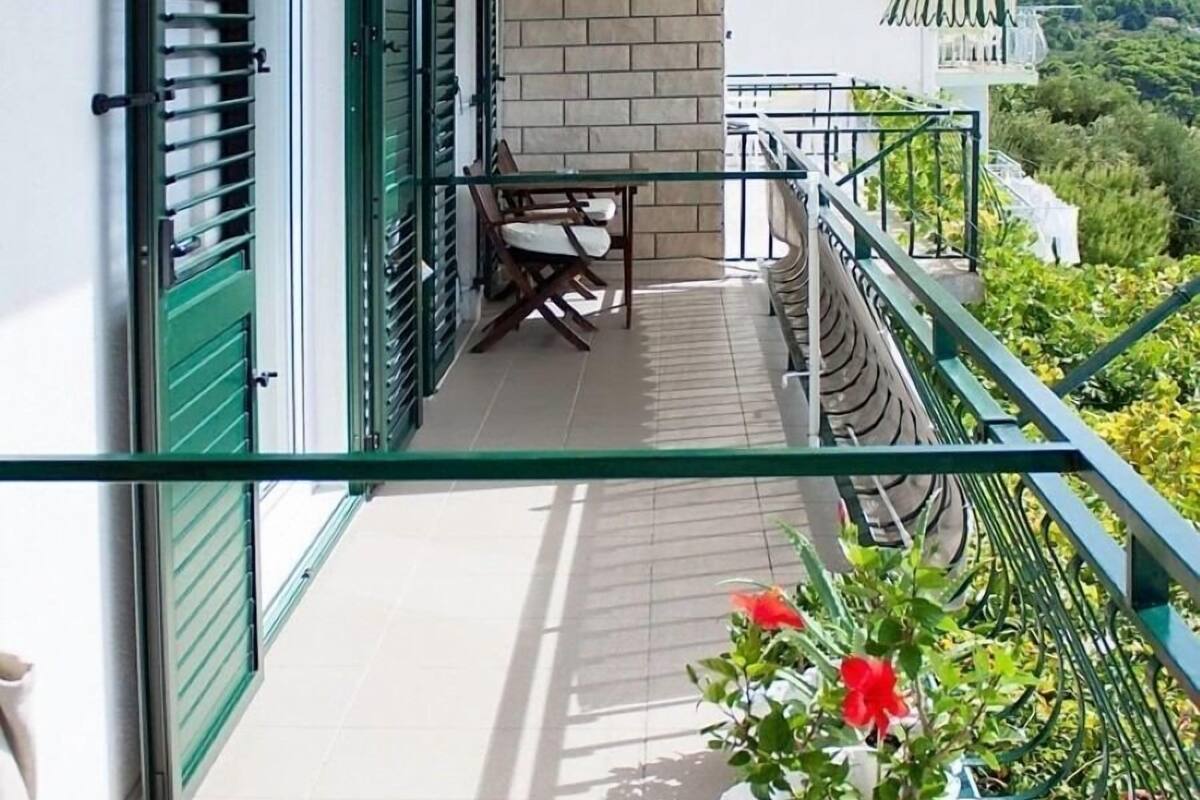 A balcony with a table and chairs, a potted plant, and a view of the landscape.
