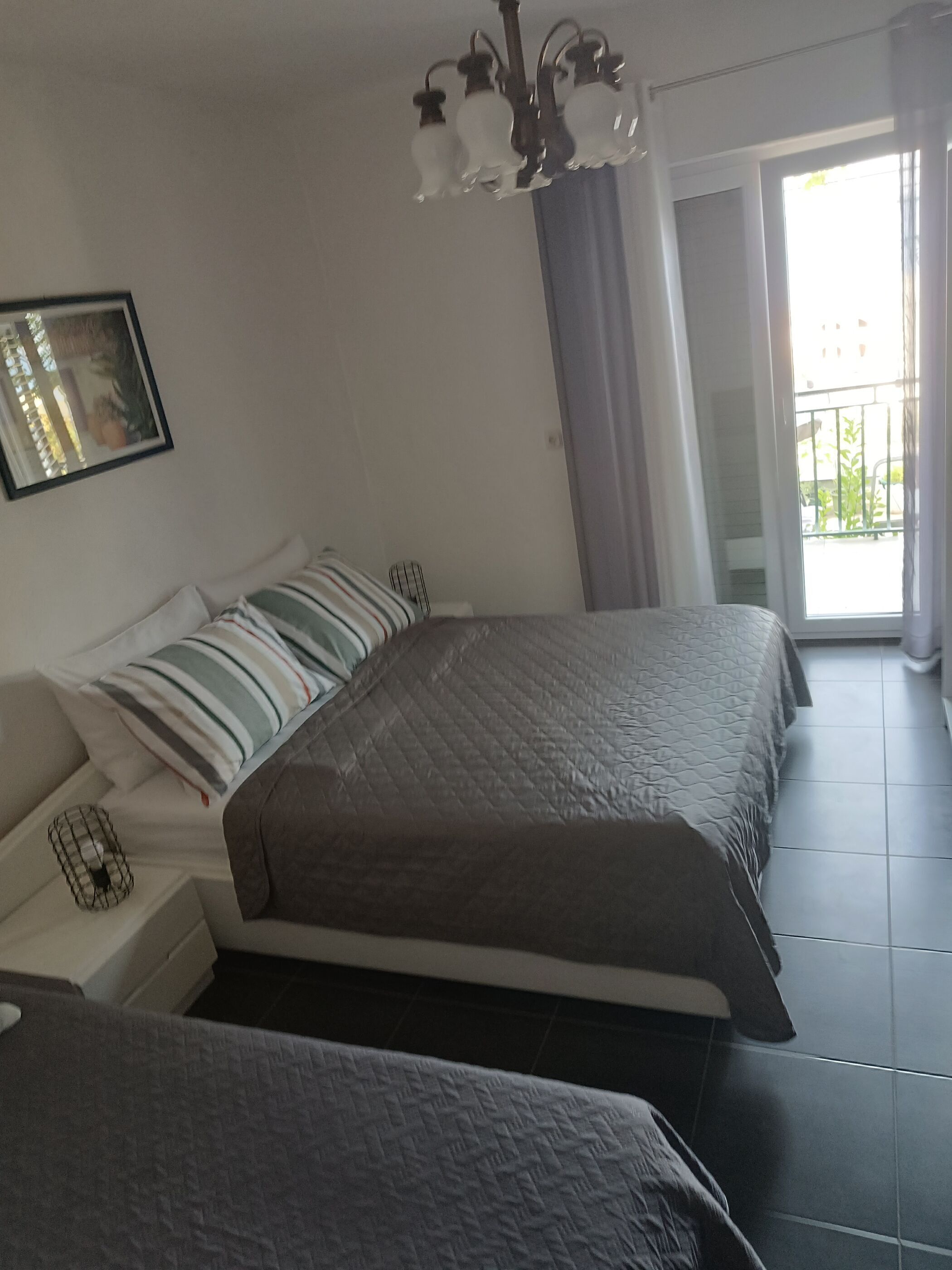 Un dormitorio con dos camas, una mesita de noche, un cuadro enmarcado en la pared y un balcón con vistas.