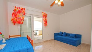 Ein Zimmer mit einem blauen Tisch, einem blauen Sofa und einem Deckenventilator.
