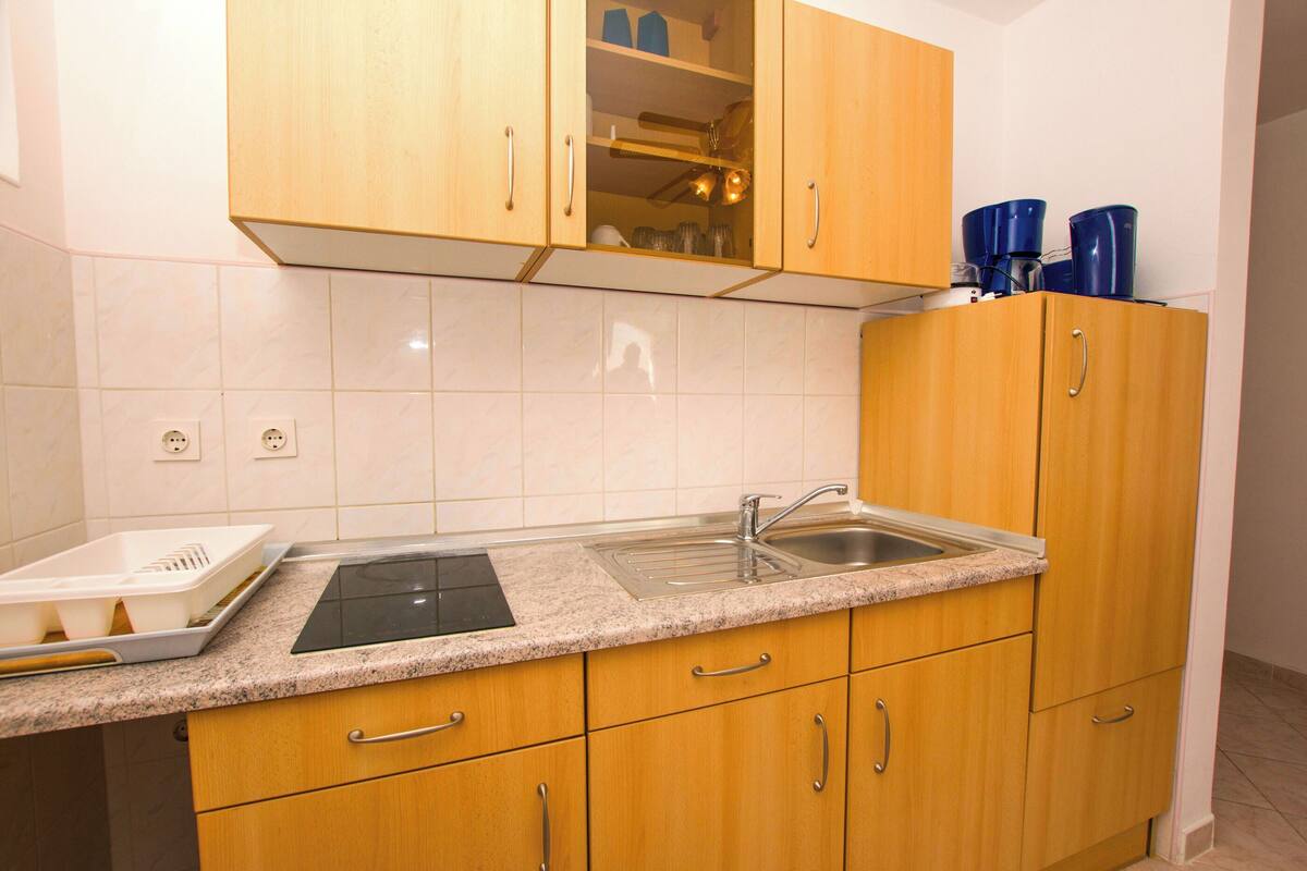 A kitchen with wooden cabinets, a granite countertop, a sink, and a coffee maker.