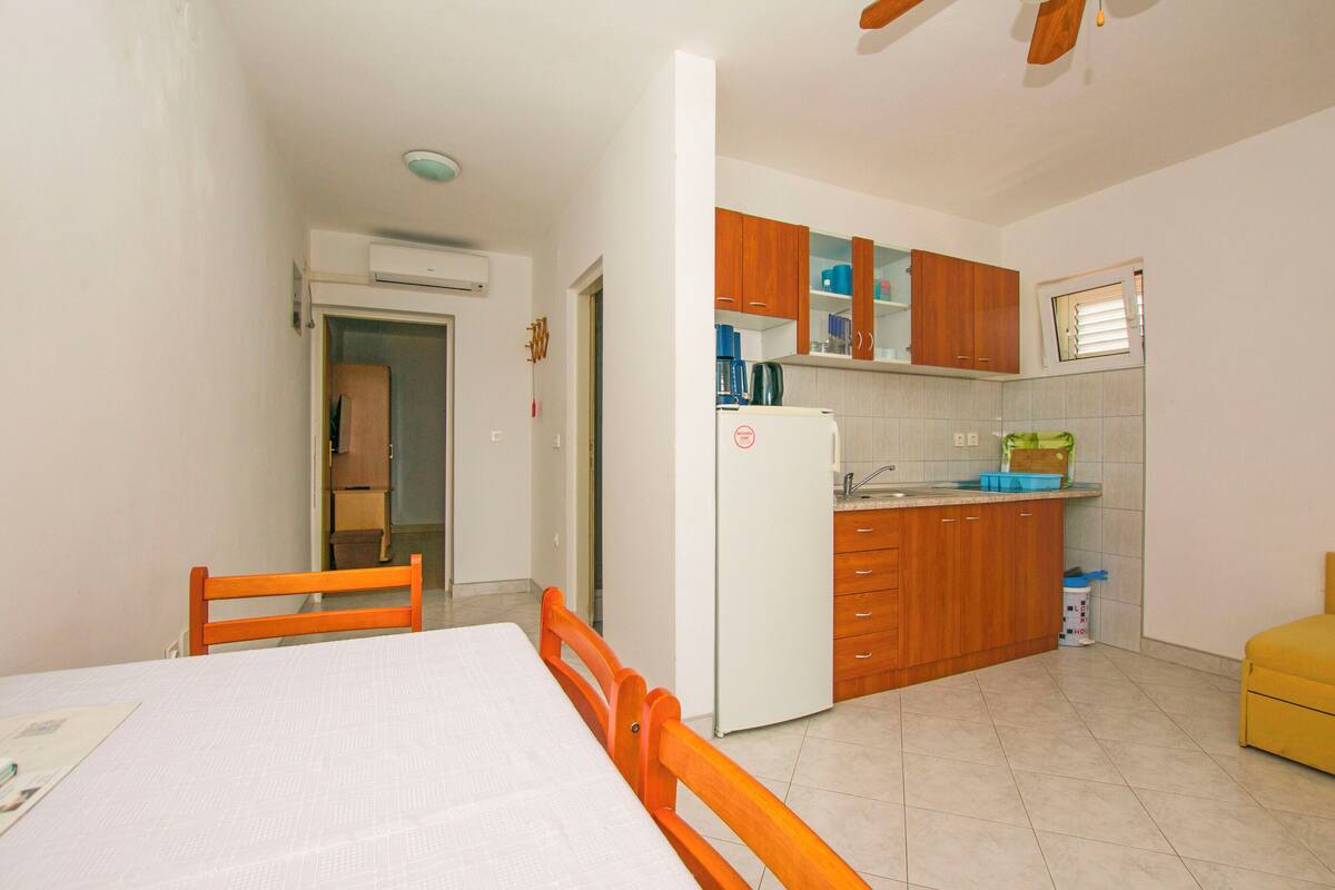 A compact kitchen with wooden cabinets, a white refrigerator, and a dining area with a table and chairs.
