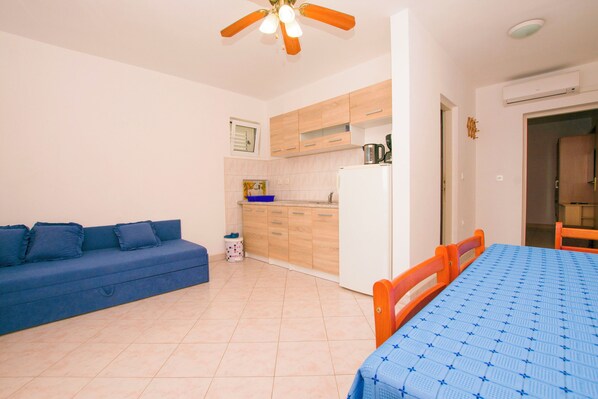 A compact living space with a sofa, a dining table, and a kitchenette. - Apartments Zaborac (Pakostane)
