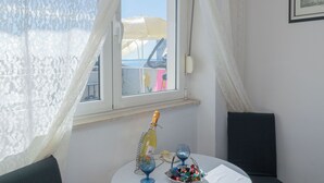Ein Zimmer mit Fenster, einer Weinflasche, zwei Gläsern und einer Schüssel mit Pralinen auf einem Tisch.