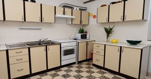 A kitchen with beige cabinets, a white stove, a microwave, and a sink. - Apartment and Rooms Tomo 1 (Gradac)