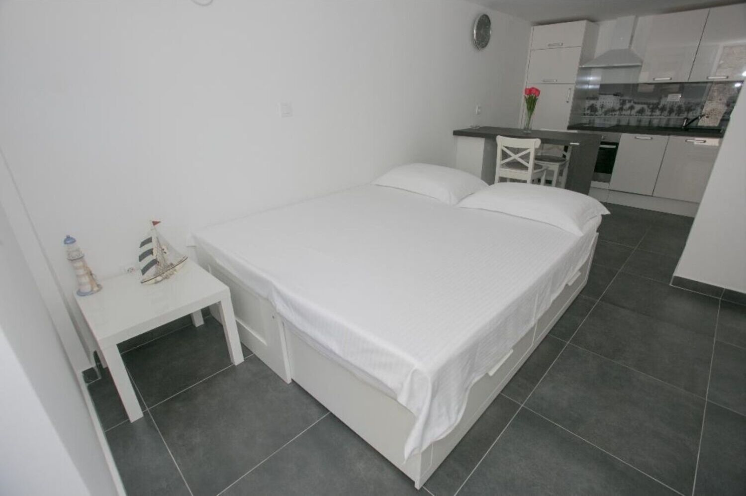 Ein kleiner, sauberer Raum mit Bett, Tisch und einer Küchenzeile.