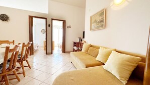 A cozy living room with a sofa, chairs, a dining table, and a painting on the wall. - Apartments Tomo (Gradac)