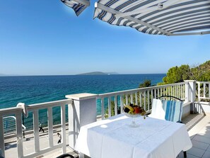 A seaside terrace with a table set for dining, overlooking the sea. - Apartments Tomo (Gradac)