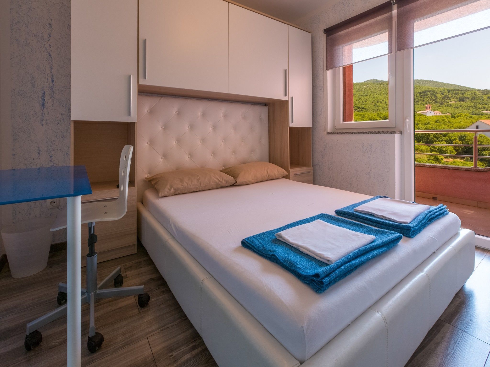 A bedroom with a bed, a desk, and a chair.