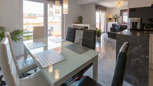 Un comedor moderno con una mesa de vidrio, sillas negras y posavasos con estampado geométrico.