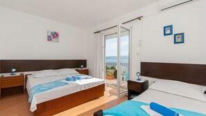 Habitación de hotel con dos camas, un balcón con vistas y un cuadro en la pared.