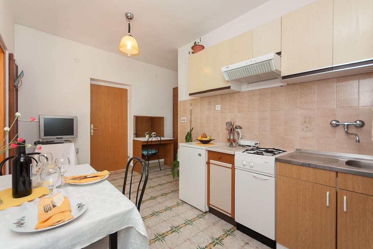 Une cuisine compacte avec un coin repas, un téléviseur et une petite table à manger pour deux personnes.