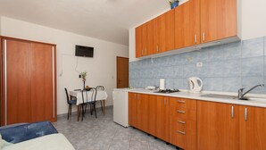Cocina compacta con armarios de madera, encimera blanca y salpicadero de azulejos.