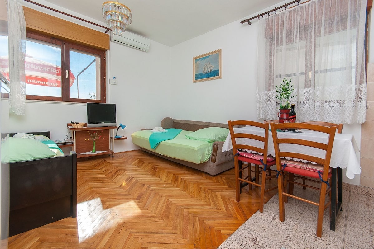 Une pièce confortable avec un lit, un bureau et une chaise, une télévision et une fenêtre avec des rideaux.