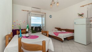 Habitación de hotel compacta con comedor, dos camas, refrigerador y vistas al exterior.