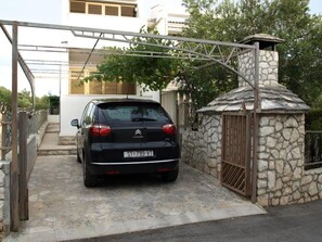 A black Citroën car parked in a gated driveway with a stone wall and metal gate. - Apartment Zeljka (Rogoznica)