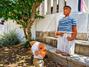 A person standing on steps with a tree and a decorative fish sculpture beside them. - Apartment Zeljka (Rogoznica)