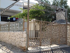A gated entrance with a stone wall and metal gate, a stone staircase, and a building with a balcony in the background. - Apartment Zeljka (Rogoznica)