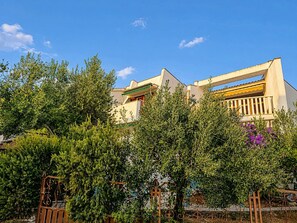 A building with a balcony, surrounded by greenery and a clear sky. - Apartment Zeljka (Rogoznica)