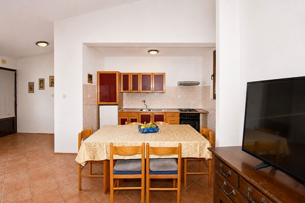 A dining area with a table, chairs, and a television. - Apartment Zeljka (Rogoznica)