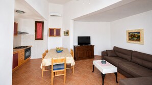 Een woonkamer met een bruine bank, een witte salontafel en een televisie.