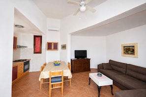 A living room with a brown sofa, a white coffee table, and a TV. - Apartment Zeljka (Rogoznica)