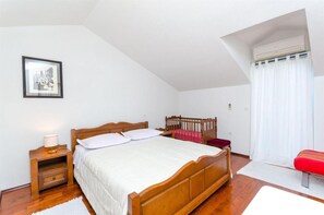 Een slaapkamer met een houten bed, een nachtkastje met een lamp, een rode bank en een raam met gordijnen.