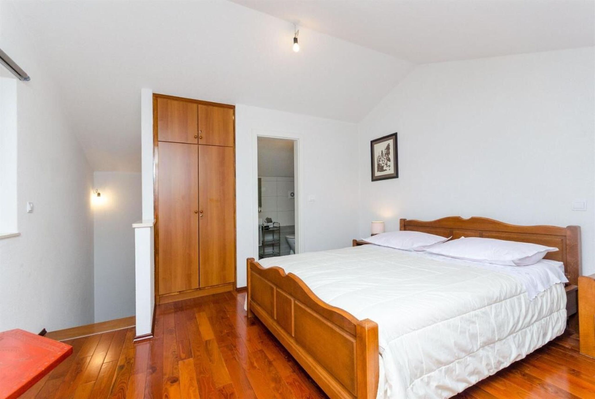 A bedroom with a wooden bed, a wardrobe, and a small table.