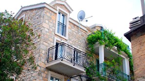 Ein Steinhaus mit Balkon, Satellitenschüssel und einer Treppe zu einer weiteren Ebene.