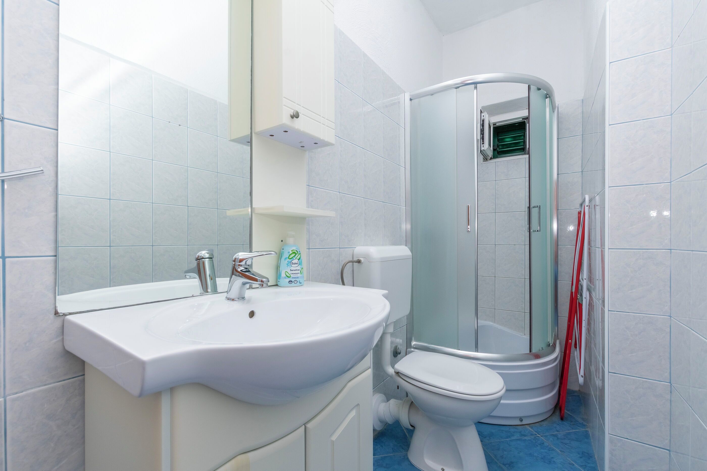 A bathroom with a white sink, toilet, and glass shower enclosure.