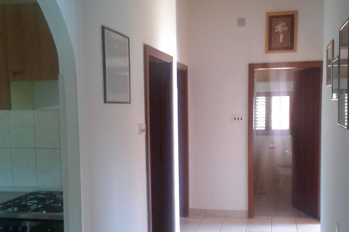 A corridor with tiled flooring, wooden doors, and a framed picture on the wall.