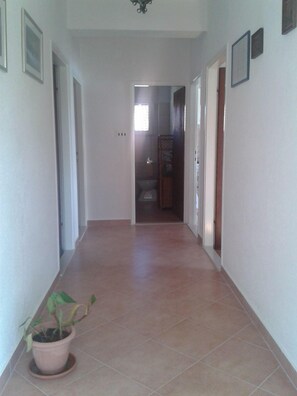 A hallway with a potted plant, tiled floor, and doors leading to other rooms. - Apartments Ivo (Sali)