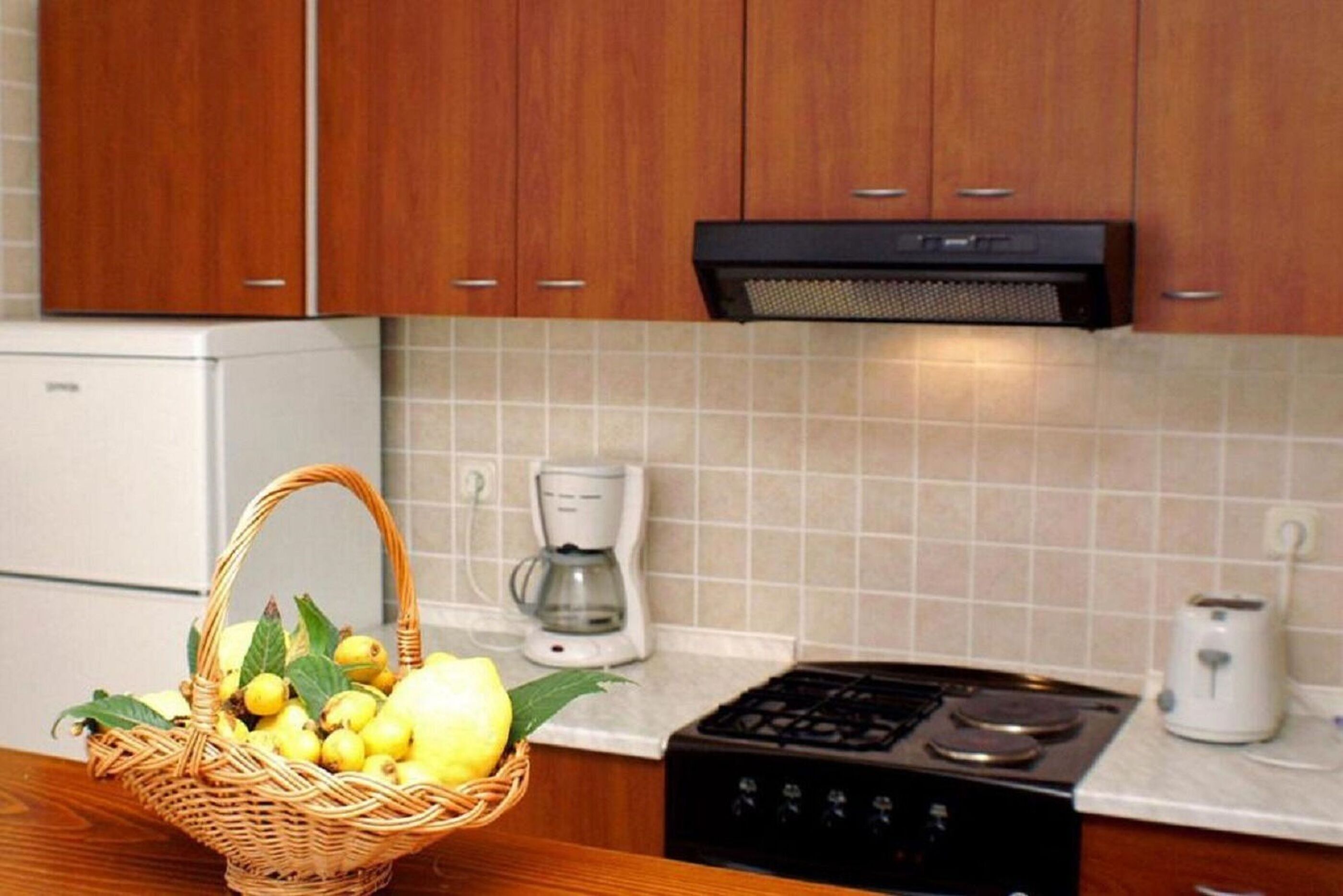 A kitchen with wooden cabinets, a gas stove, a coffee maker, and a toaster.