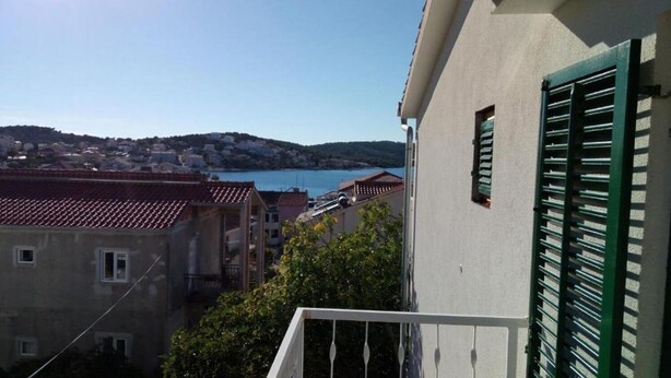 A view of a coastal town with buildings, a body of water, and hills in the background. - Apartment Marijica (Okrug)