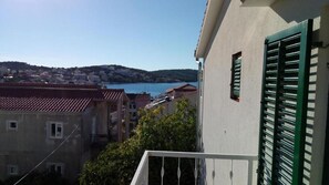 A view of a coastal town with buildings, a body of water, and hills in the background. - Apartment Marijica (Okrug)