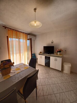 Un espacio habitable compacto con comedor, kitchenette y televisor.
