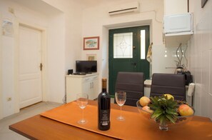 Uma sala de jantar com uma mesa, duas taças de vinho, uma garrafa de vinho e uma tigela de fruta.