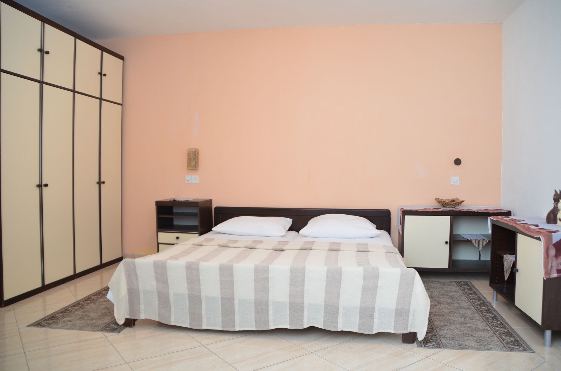Ein Schlafzimmer mit Bett, Kleiderschrank, Schreibtisch und einem kleinen Schrank.