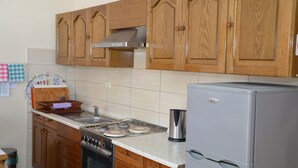 Une cuisine avec des armoires en bois, une cuisinière en acier inoxydable, un réfrigérateur et un dosseret carrelé.