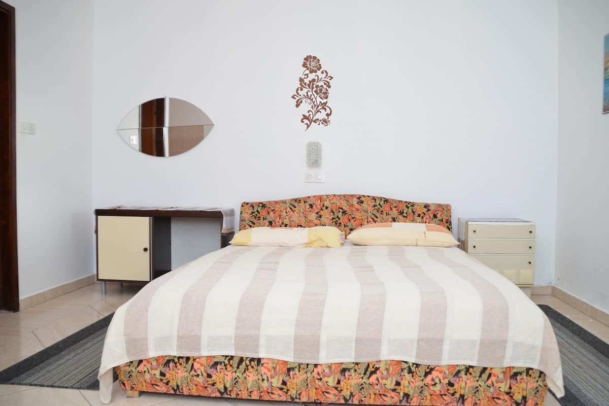 Une chambre à coucher avec un lit, un bureau, une commode et un miroir au mur.