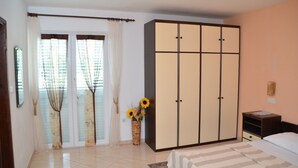 Une chambre à coucher avec un lit, une armoire, une fenêtre avec des rideaux et un vase rempli de tournesols.