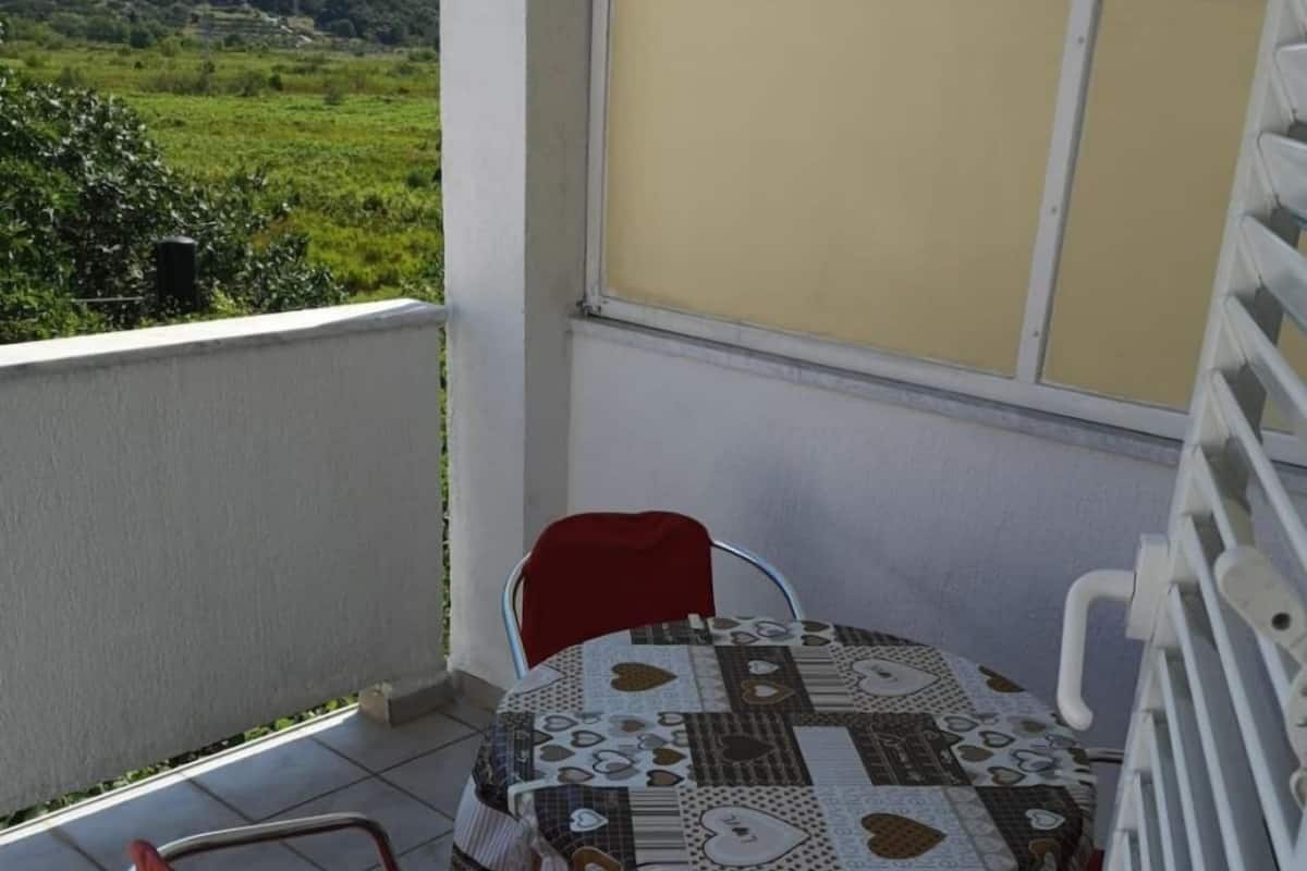 Un balcon avec une table et des chaises, une vue sur la campagne et une balustrade blanche.