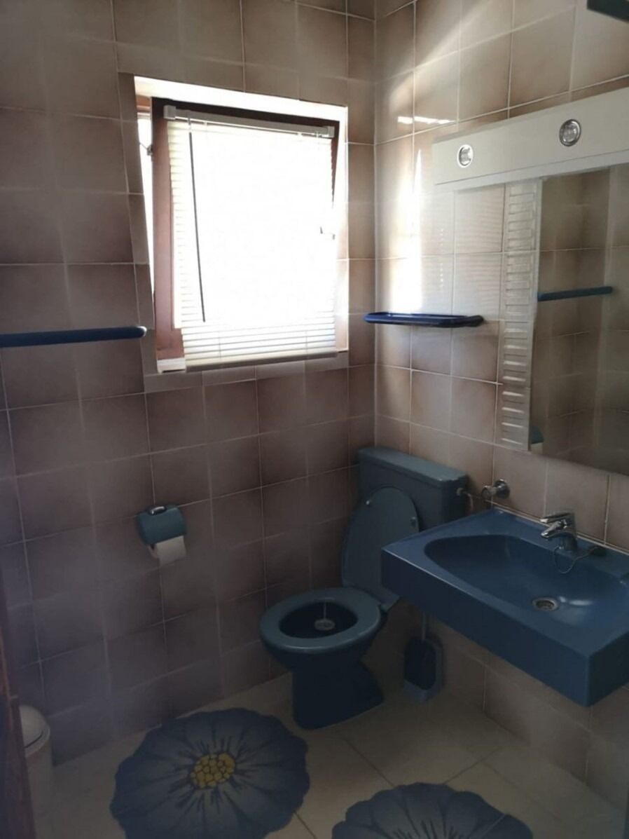 A bathroom with a toilet, sink, and window.