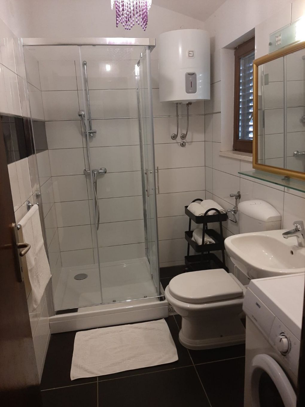 Une salle de bain moderne avec une douche à parois de verre, des toilettes, un lavabo et un lave-linge.