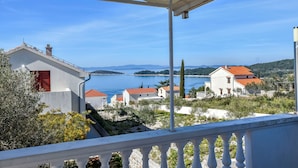 Blick auf die Küste vom Balkon mit Meer, Häusern und Bergen im Hintergrund.