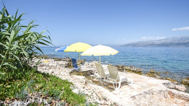 Eine Küstenterrasse mit Sitzgelegenheiten und Sonnenschirmen mit Blick aufs Meer.