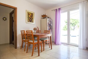 Un comedor con una mesa y sillas de madera, un cuadro en la pared y un refrigerador con imanes.
