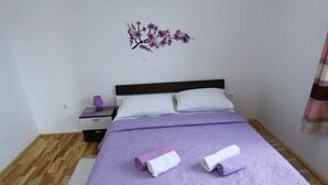 Una camera da letto con un letto, due cuscini, un comodino con una lampada e un elemento decorativo a parete.